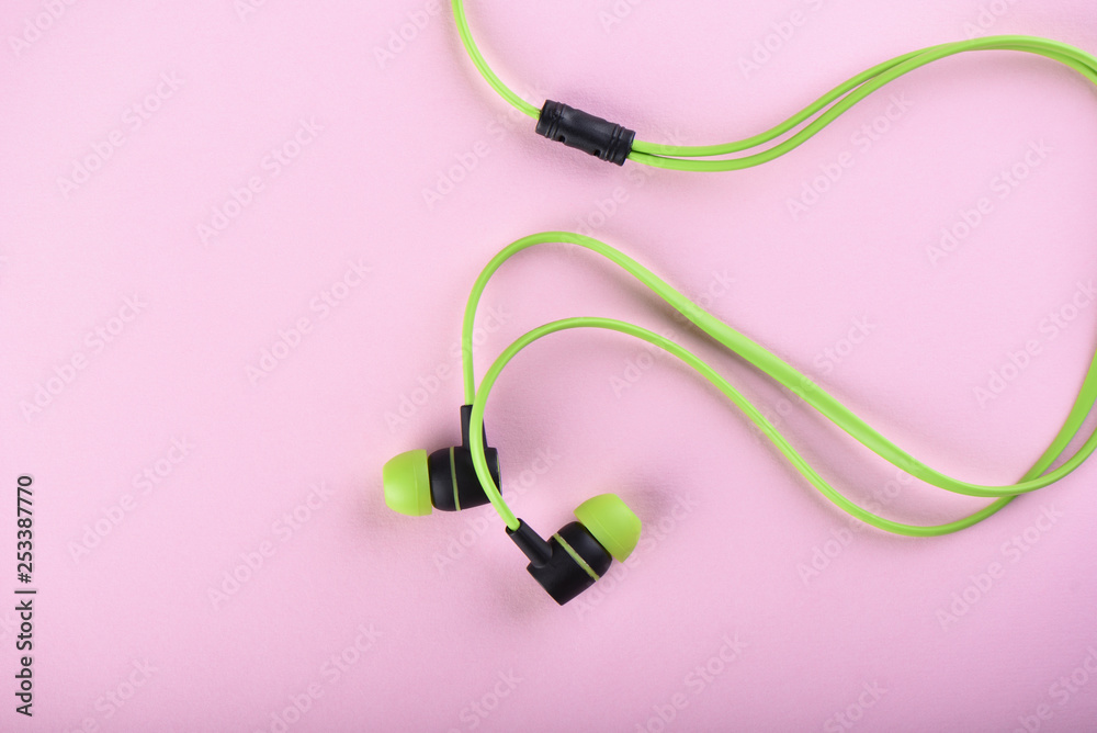 Green headphones or earphones isolated on a pink background Green headphones or earphones isolated on a pink background