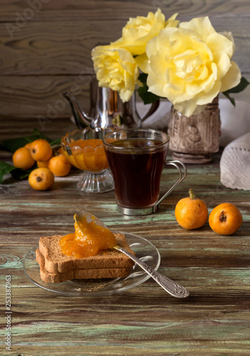 Branch with fruits medlars, jam and tea on a wooden table photo