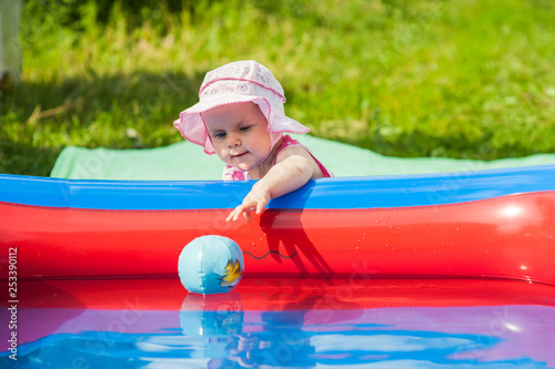 Baby plays near the inflatable pool on a hot summer day