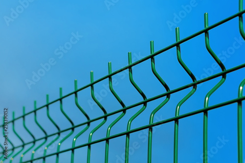 Steel lattice fence. Metal wire fence with blue sky in the background.