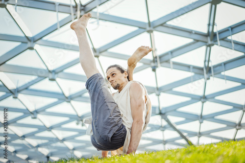 Close up of attractive athletic man practicing yoga and warming up outdoors.