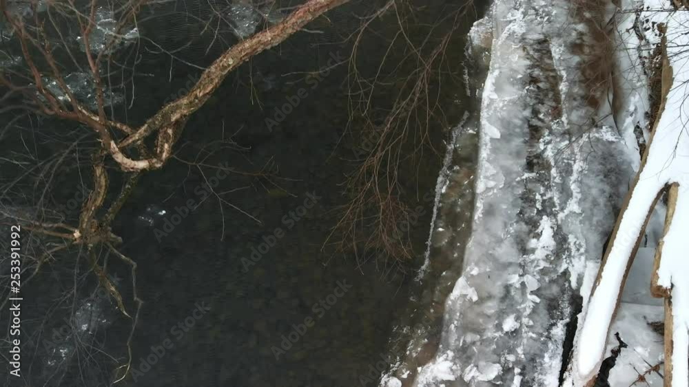 Tree Hanging Over Snowy River Bank by Icy Water AERIAL FLY UP SLOW MOTION Tree Hanging Over Snowy River Bank by Icy Water AERIAL FLY UP SLOW MOTION