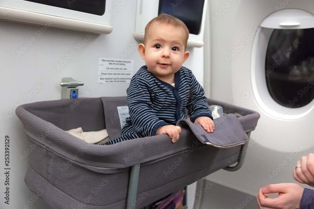 Infant girl sit in special baby bassinet in airplane. is laugh and amazed, it is her first flight Stock Photo | Adobe Stock