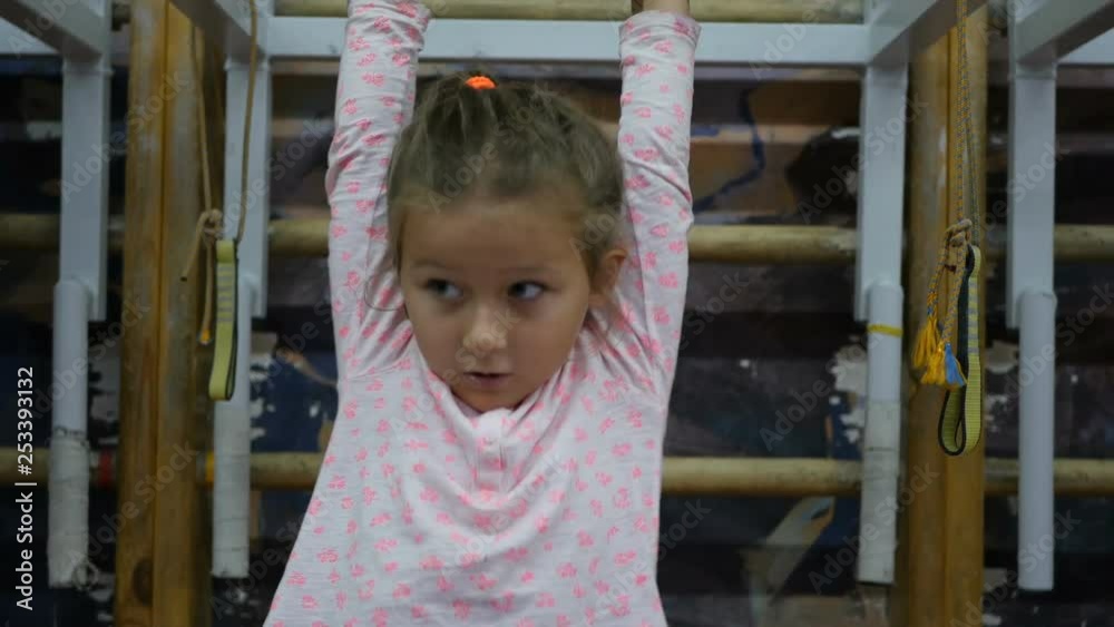 Kid is engaged in gymnastics at the sports hall. Child on horizontal bar Kid is engaged in gymnastics at the sports hall. Child on horizontal bar