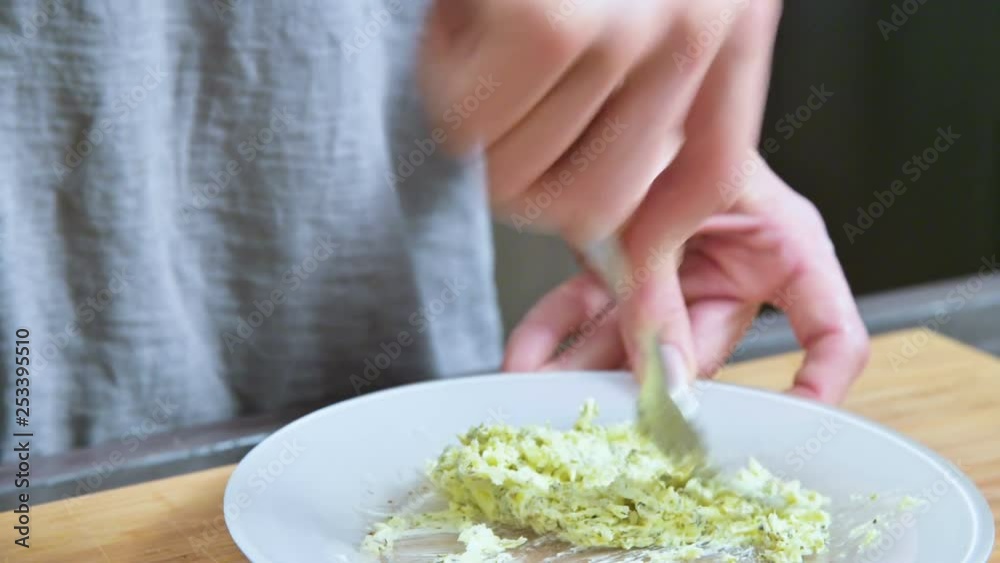 Close-up of female hands with a fork stirred the butter with spices. Home kitchen. For the sauce Close-up of female hands with a fork stirred the butter with spices. Home kitchen. For the sauce