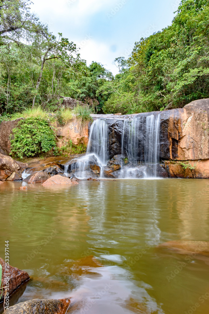 Fototapeta premium Waterfall and lake in rain forest of Moeda in Minas Gerais state on cloudy day among rocks and vegetation
