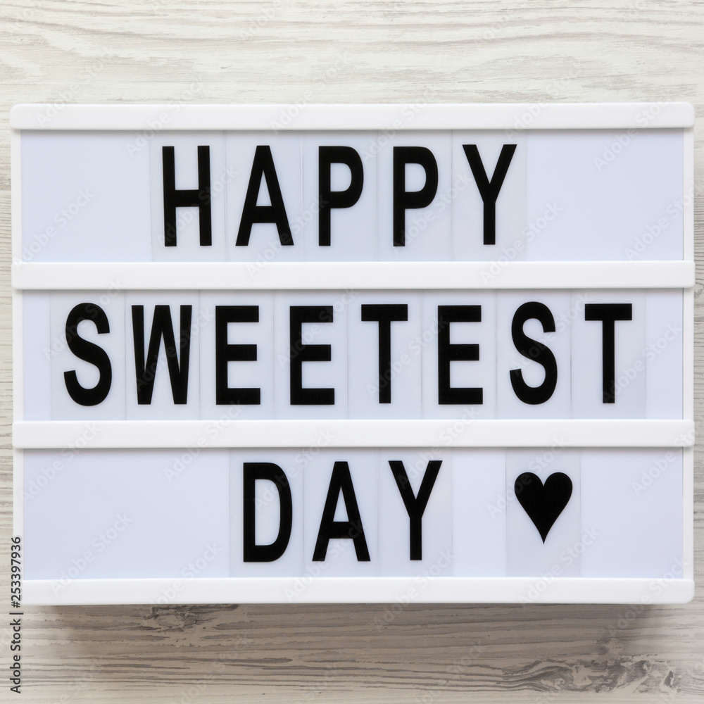 'Happy Sweetest Day' word on modern board over white wooden background, top view. From above, flat lay, overhead.