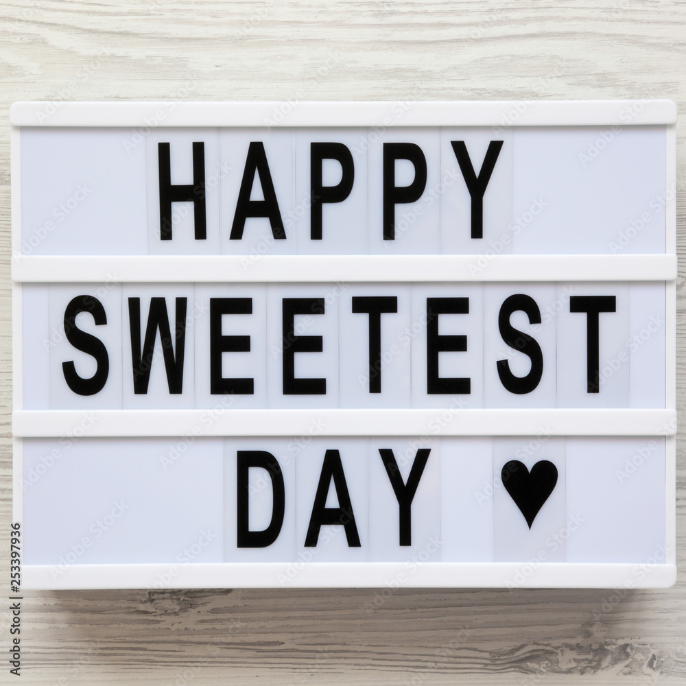 'Happy Sweetest Day' word on modern board over white wooden background, top view. From above, flat lay, overhead. 'Happy Sweetest Day' word on modern board over white wooden background, top view. From above, flat lay, overhead.