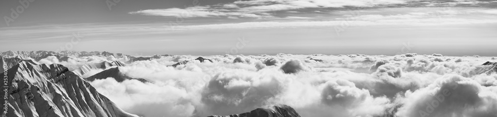 Obraz premium Panorama of snowy mountains covered with sunlight clouds at winter