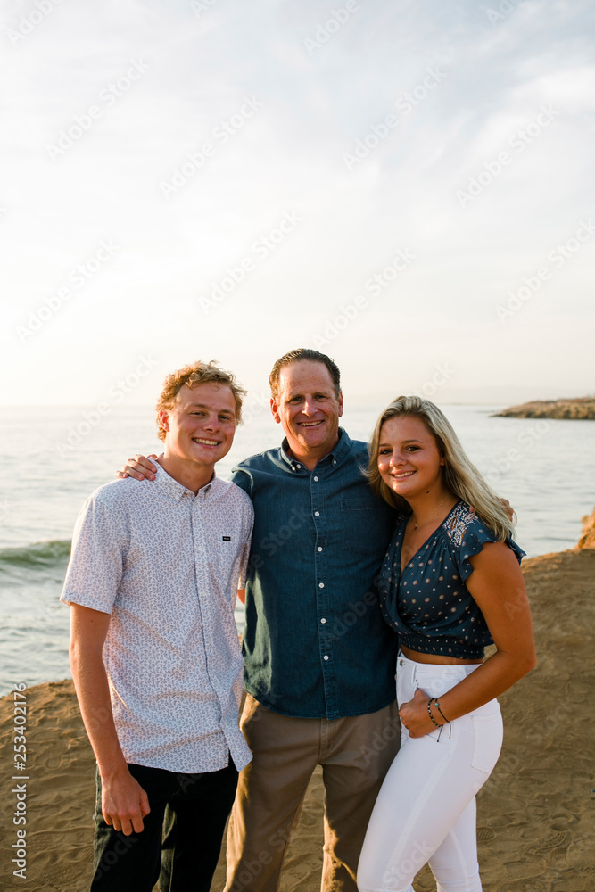 Portrait of happy father with children standing on cliff against sea during sunset Portrait of happy father with children standing on cliff against sea during sunset