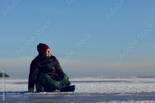Traveler sitting in the snow and smiling looking at the sun