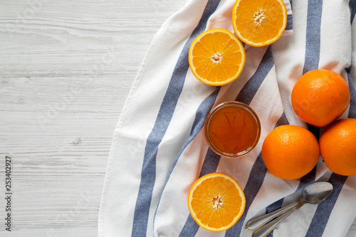 Glass jar of homemade orange marmelade on a white wooden surface, top view. Flat lay, overhead, from above. Copy space. photo