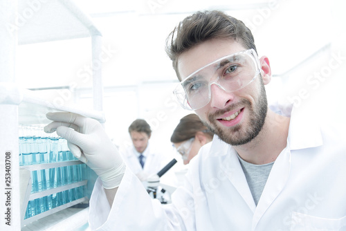 Young male scientist looking at a sample in a test tube side vie
