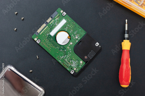 hard disk drive and set of screwdriver at black background. repair hdd after diagnostics. data maintenance after virus attack.