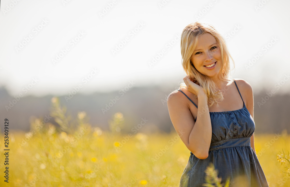 Portrait of woman in a blue dress standing in a meadow. Portrait of woman in a blue dress standing in a meadow.