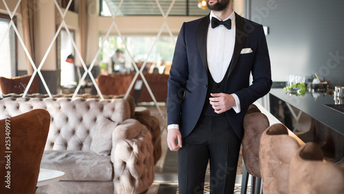 Foto Man in expensive custom tailored suit, tuxedo standing and posing inside luxury