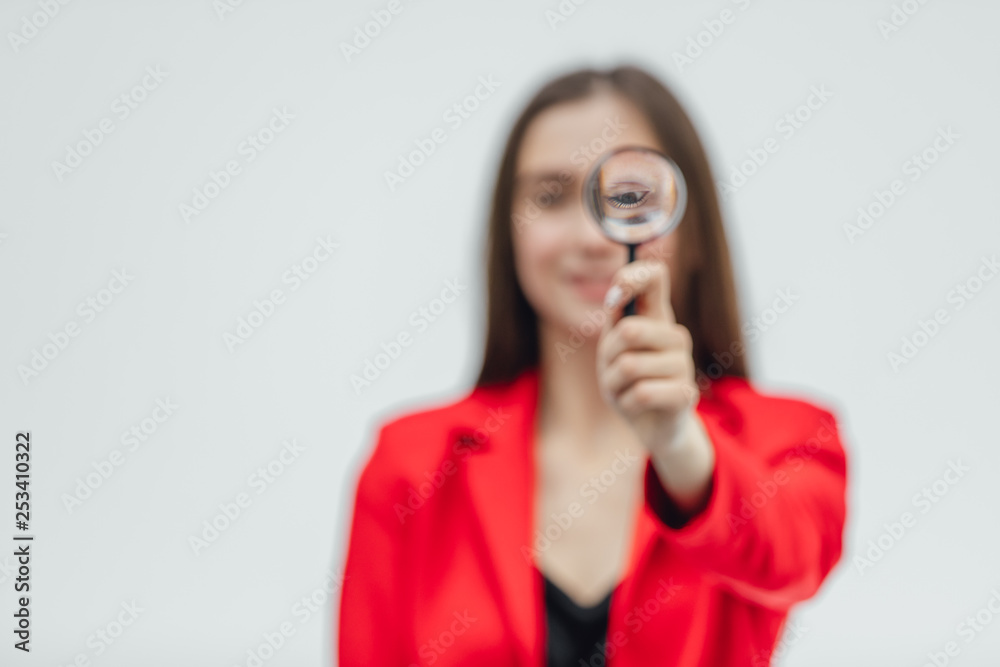 Funny expressions. Shocked woman looking at magnifying glass. A surprised girl looks at opening the keys with big eyes through a magnifying glass, isolated on a white background. Funny expressions. Shocked woman looking at magnifying glass. A surprised girl looks at opening the keys with big eyes through a magnifying glass, isolated on a white background.