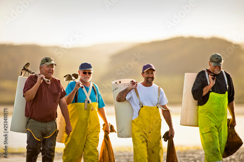 Group of fisherman on the beach with bags of shellfish.