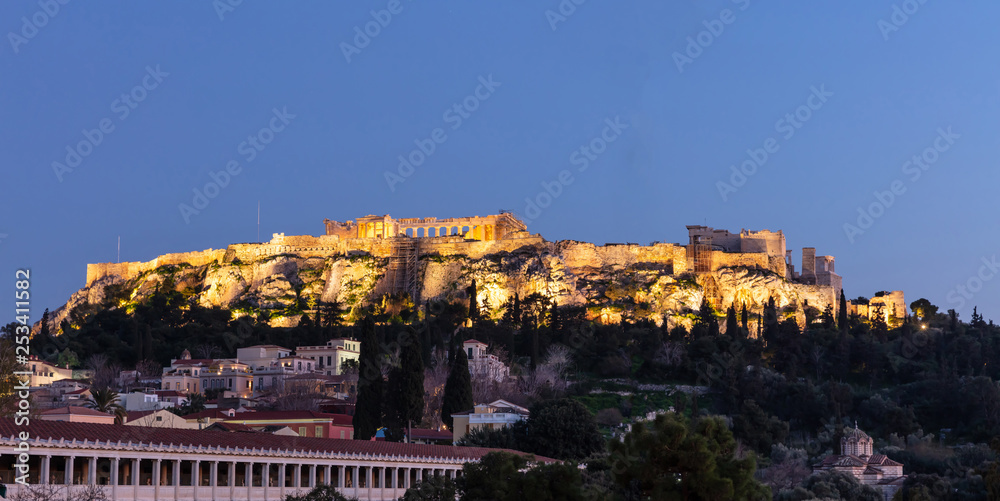 Acropolis of Athens Greece rock and Parthenon illuminated, blue sky background late in the evening.