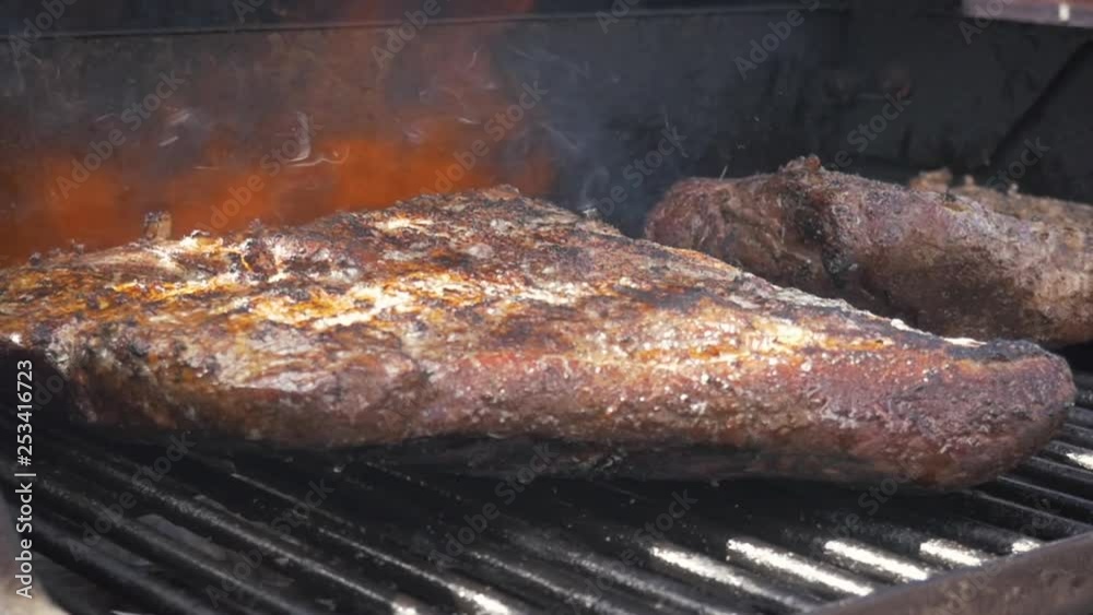 Flame grilling barbecue beef brisket in slow motion. Flames shoot from