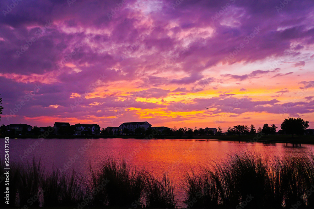 Purple, pink, yellow and red cloudy sunset over a lake.