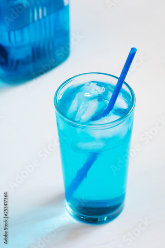 Glass with a blue cocktail with ice on a white background.