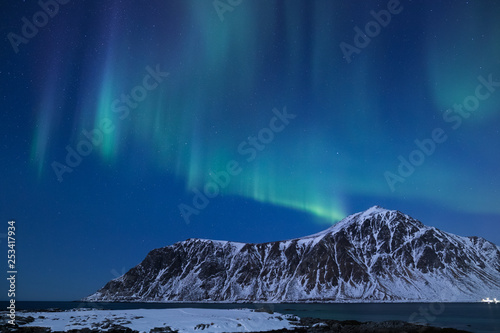 Beautiful northern lights over the snow covered winter landscape of the Lofoten islands