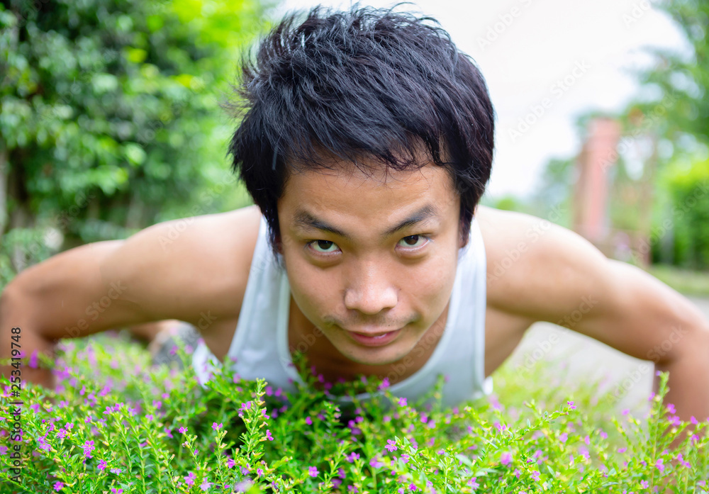 Thai man in white tank top standing in the garden Thai man in white tank top standing in the garden