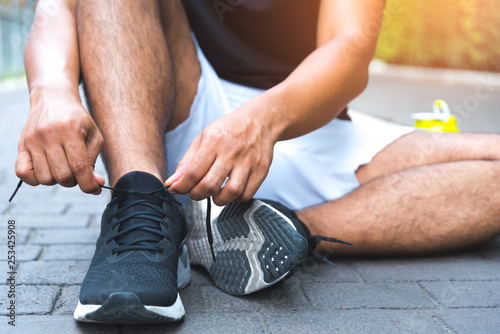 Athlete male hands tying shoelace on running shoes