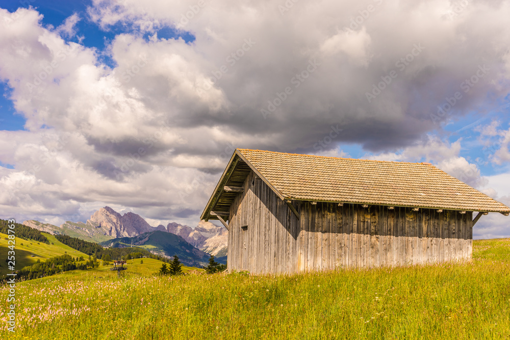 Alpe di Siusi, Seiser Alm with Sassolungo Langkofel Dolomite, an old barn in a field Alpe di Siusi, Seiser Alm with Sassolungo Langkofel Dolomite, an old barn in a field