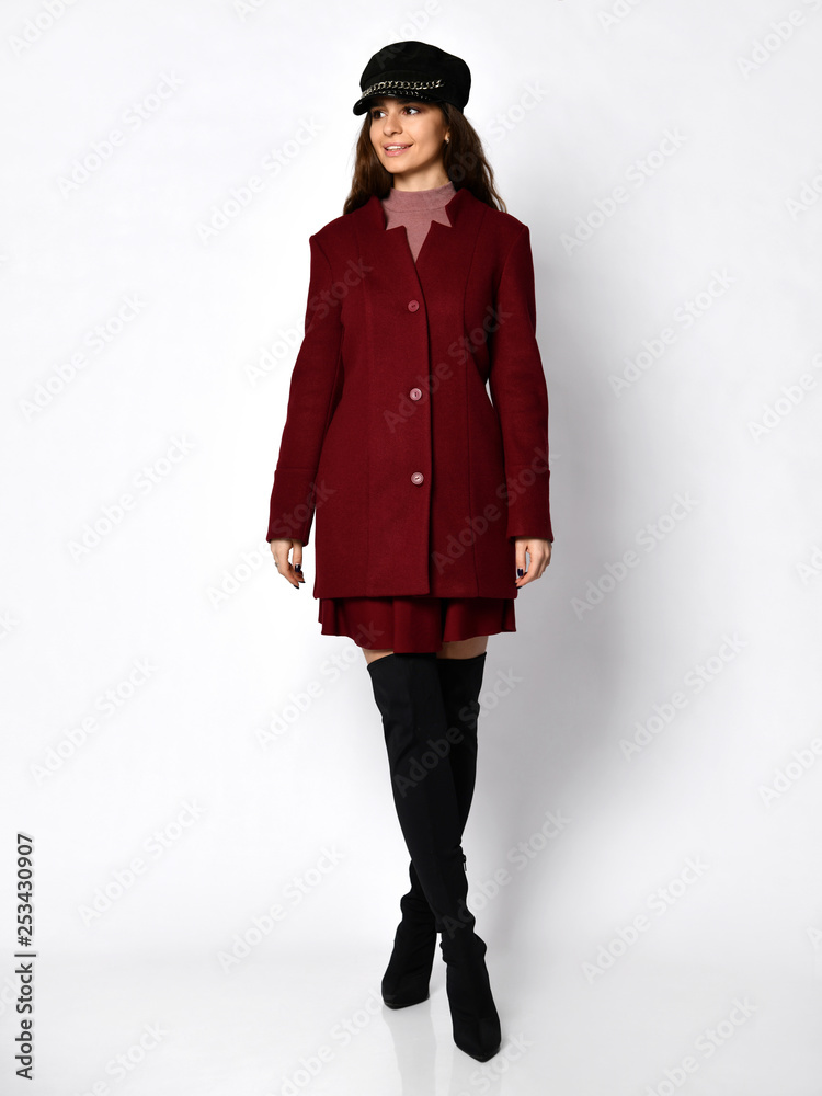 Young beautiful woman posing in new long fashion casual dark red winter jacket coat and cap hat full body Young beautiful woman posing in new long fashion casual dark red winter jacket coat and cap hat full body