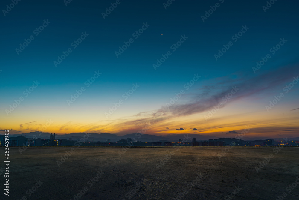 Fototapeta premium Empty concrete cement floor with dramatic sunrise blue and yellow sky .