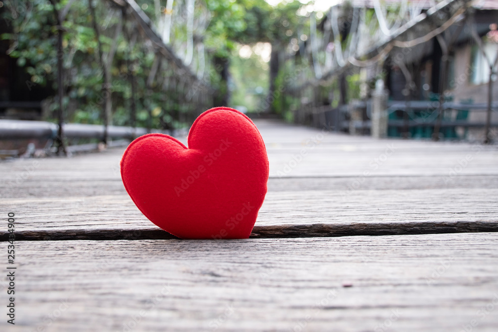 red heart on wooden bridge across the river, surrounded with green tree red heart on wooden bridge across the river, surrounded with green tree