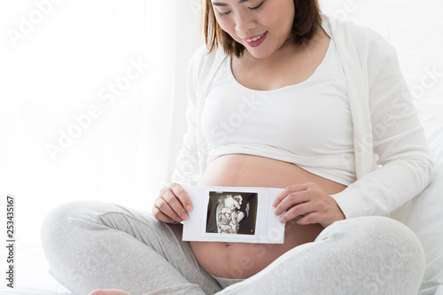 Pregnant women holding four-dimensional ultrasound images on hand, Techniques and abdominal applications, Prenatal diagnosis concept, Asian pregnancy woman model photo