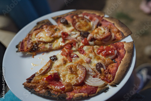 White plate with pizza slices. Salami and cheese pizza with crust