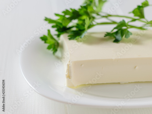 Serbian cheese with parsley leaves on a white table on a white background. The view from the top. Dairy product.