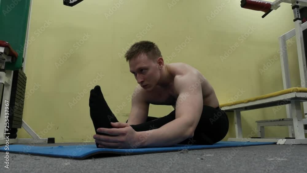 Sporty man stretching arm before gym workout. Fitness strong male athlete standing indoor warming up Sporty man stretching arm before gym workout. Fitness strong male athlete standing indoor warming up