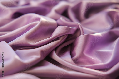 Close up pink fabric. The purple fabric is laid out waves. Fuchsia sateen fabric for background or texture.