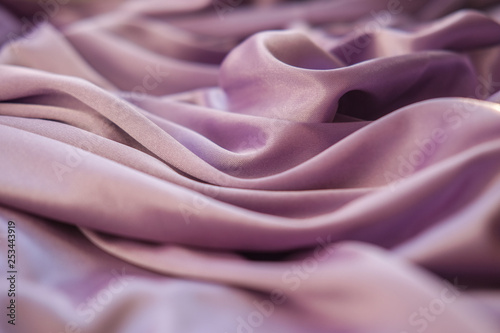 Close up pink fabric. The purple fabric is laid out waves. Fuchsia sateen fabric for background or texture.