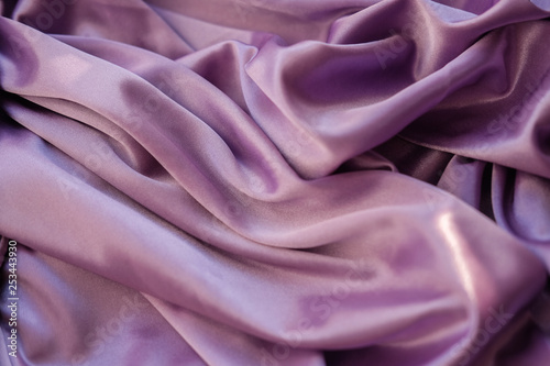 Close up pink fabric. The purple fabric is laid out waves. Fuchsia sateen fabric for background or texture.