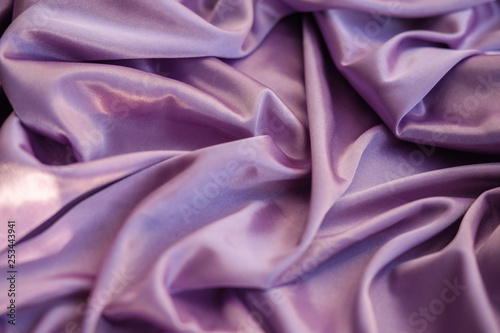 Close up pink fabric. The purple fabric is laid out waves. Fuchsia sateen fabric for background or texture.