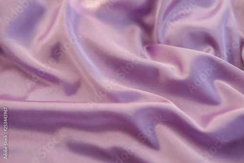 Close up pink fabric. The purple fabric is laid out waves. Fuchsia sateen fabric for background or texture.