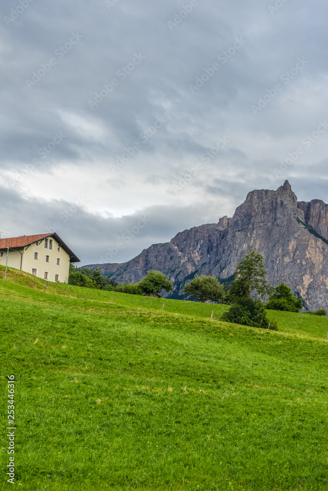 Alpe di Siusi, Seiser Alm with Sassolungo Langkofel Dolomite, a house with a mountain in the background Alpe di Siusi, Seiser Alm with Sassolungo Langkofel Dolomite, a house with a mountain in the background