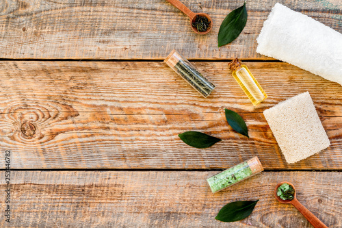 Tea tree spa composition. Fresh tea tree leaves, natural cosmetics, towel on rustic wooden background top view copy space border