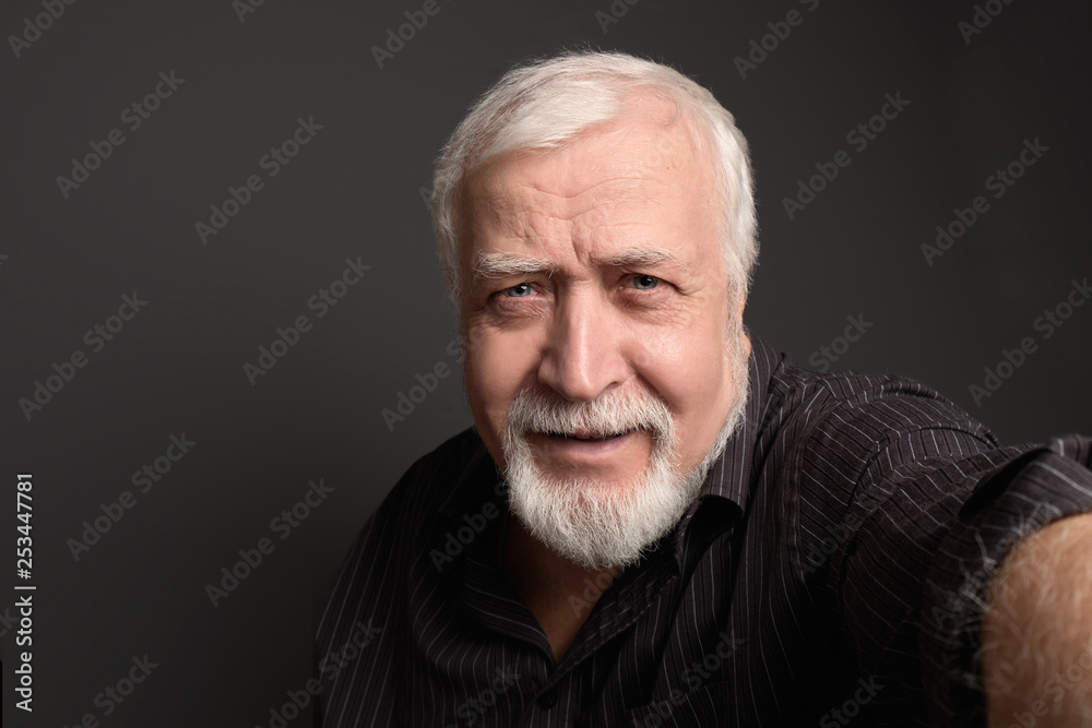 good-natured charismatic man on a gray background makes a selfie on the camera good-natured charismatic man on a gray background makes a selfie on the camera