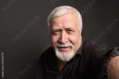 good-natured charismatic man on a gray background makes a selfie on the camera