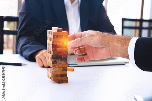 Body part Business engineers plays Jenga game and Orange hat. They are sitting in office and play game.Photo concept for engineering and work.