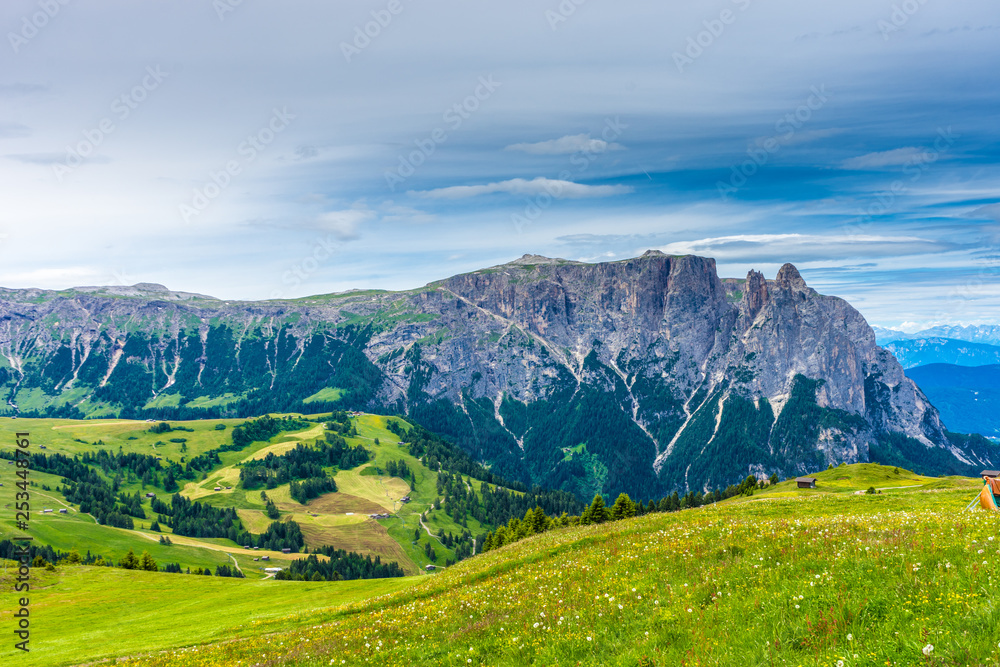 Alpe di Siusi, Seiser Alm with Sassolungo Langkofel Dolomite, a large green field with a mountain in the background Alpe di Siusi, Seiser Alm with Sassolungo Langkofel Dolomite, a large green field with a mountain in the background