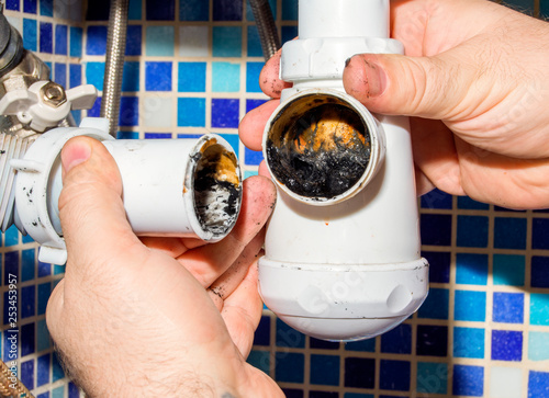 фотографія The plumber disassembles the siphon under the sink to clean it from dirt