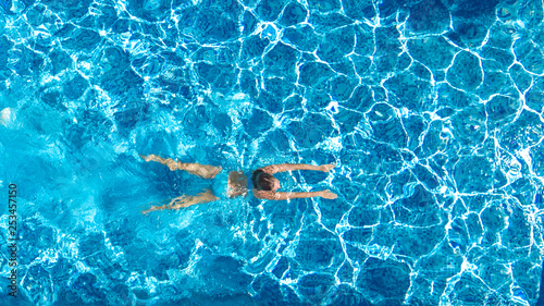 Active girl in swimming pool aerial drone view from above, young woman swims in blue water, tropical vacation, holiday on resort concept